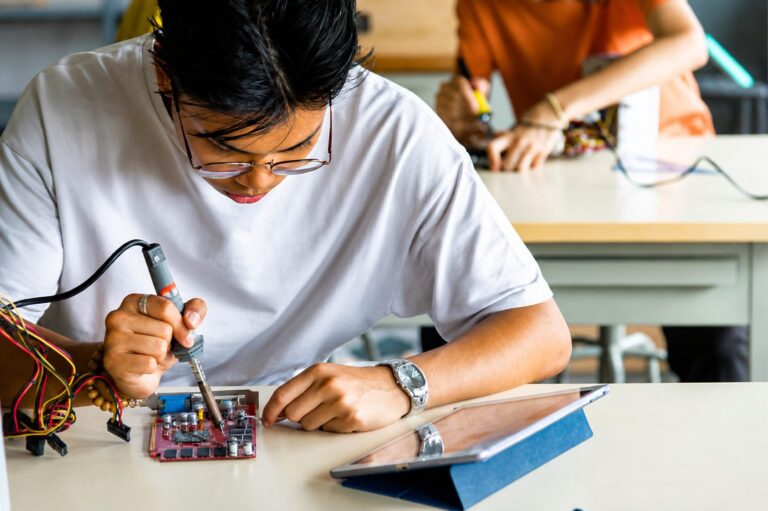 Student soldering electronic components in vocational technical training