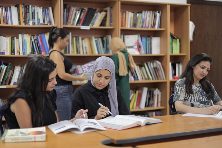 Instructor teaching group of students at table with branded CIS display wall behind
