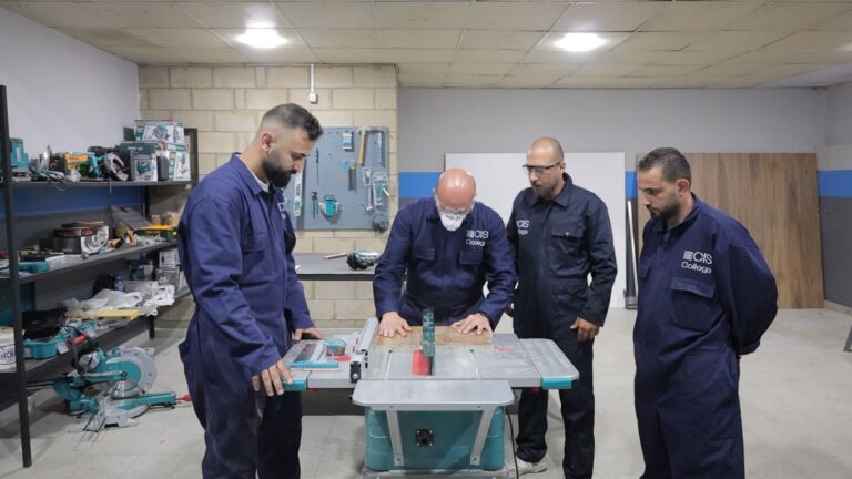 Technicians in branded uniforms collaborating at workshop workbench with training materials